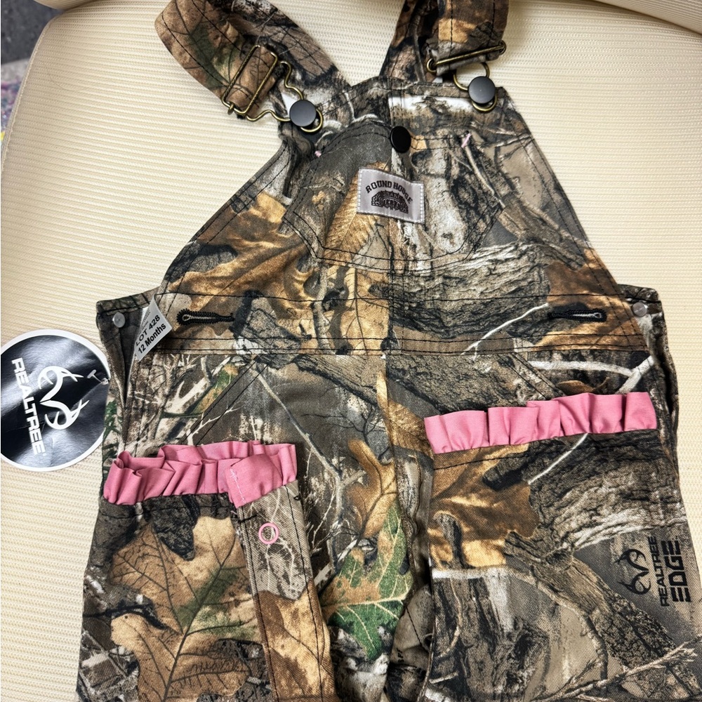 Brand new! Toddler girls Real Tree camo overalls with pink lace ankle detail.